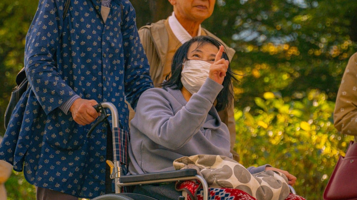 휠체어에 앉은 어르신과 함께 걷는 동행인